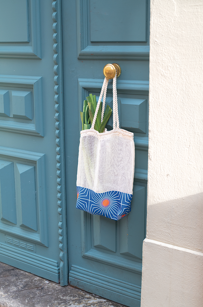 Our jute tote bag hanging from a blue door.